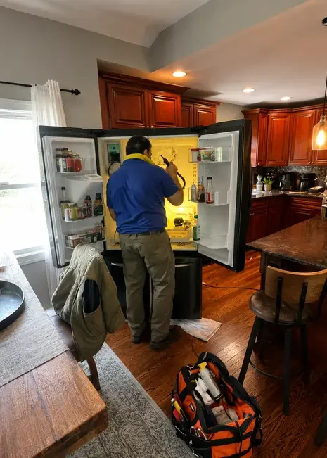 Appliance technician repairing a refrigerator in a Long Island home