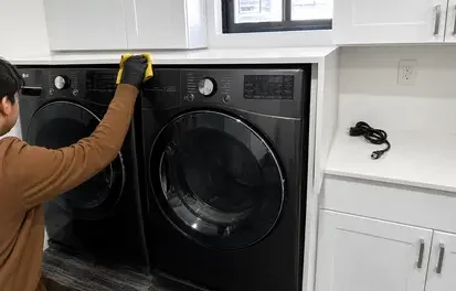 Appliance technician inspecting a washer and dryer in a Long Island home